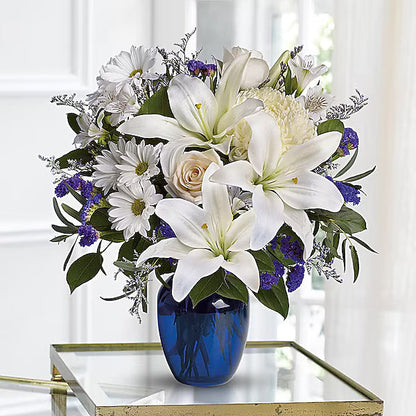 Bouquet of colorful flowers arranged in a blue vase on a glass table