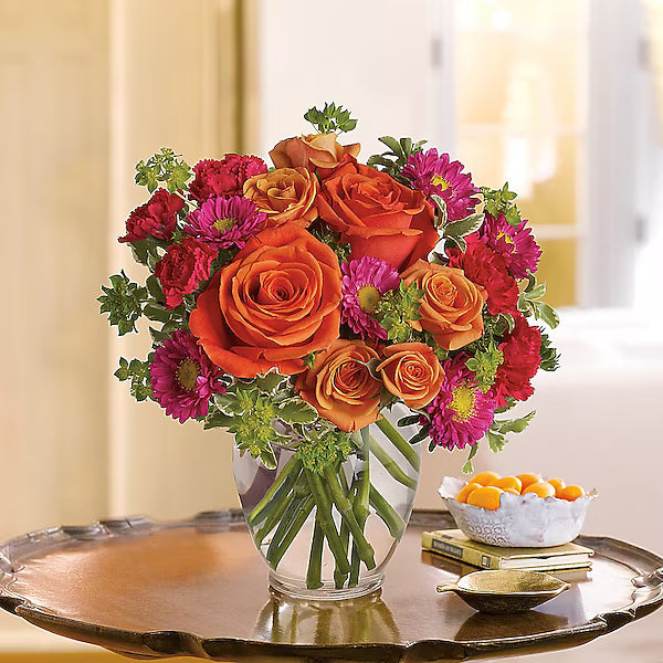 Bright bouquet of orange and pink flowers in a clear vase