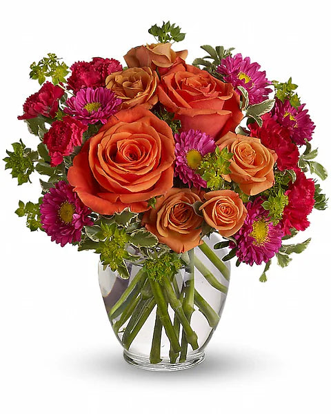 clear glass vase holding a bouquet of vibrant orange and pink flowers.