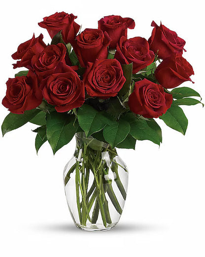 Glass vase holding red roses.